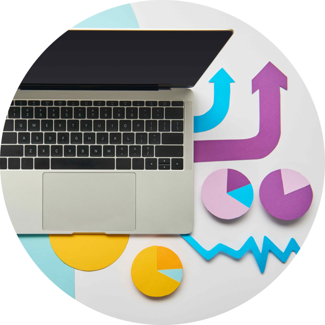 laptop på ett bord intill olika pappersutklipp av grafer